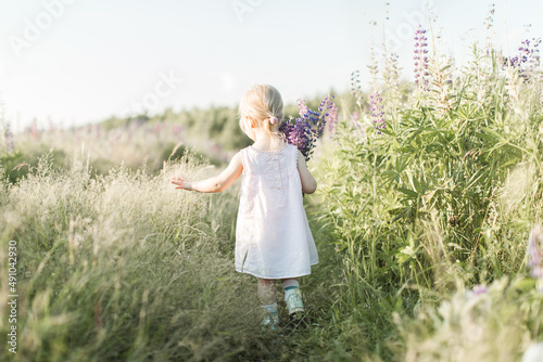 a child walks in a field with a bouquet of flowers