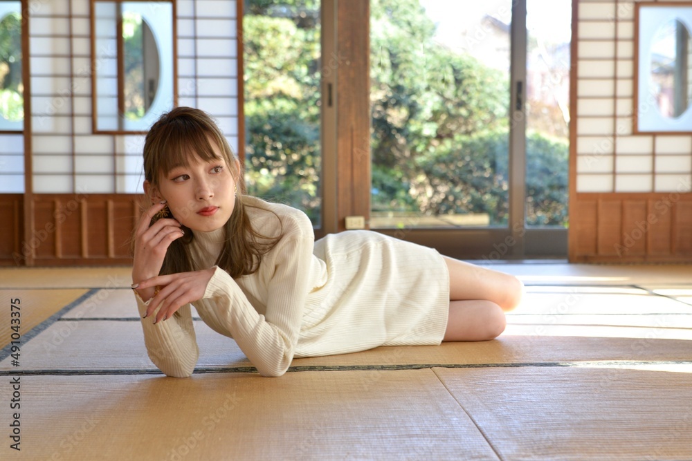 畳の上に横たわり頬杖をつく白いワンピースを着た若い女性 畳の上に横たわり頬杖をつく白いワンピースを着た若い女性
