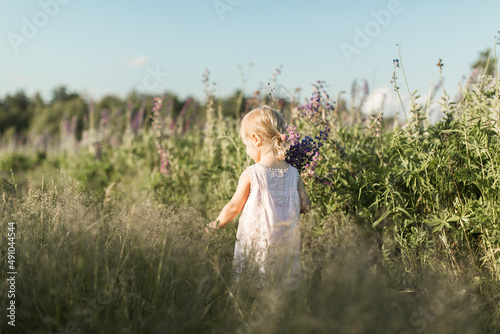 a child walks in a field with a bouquet of flowers