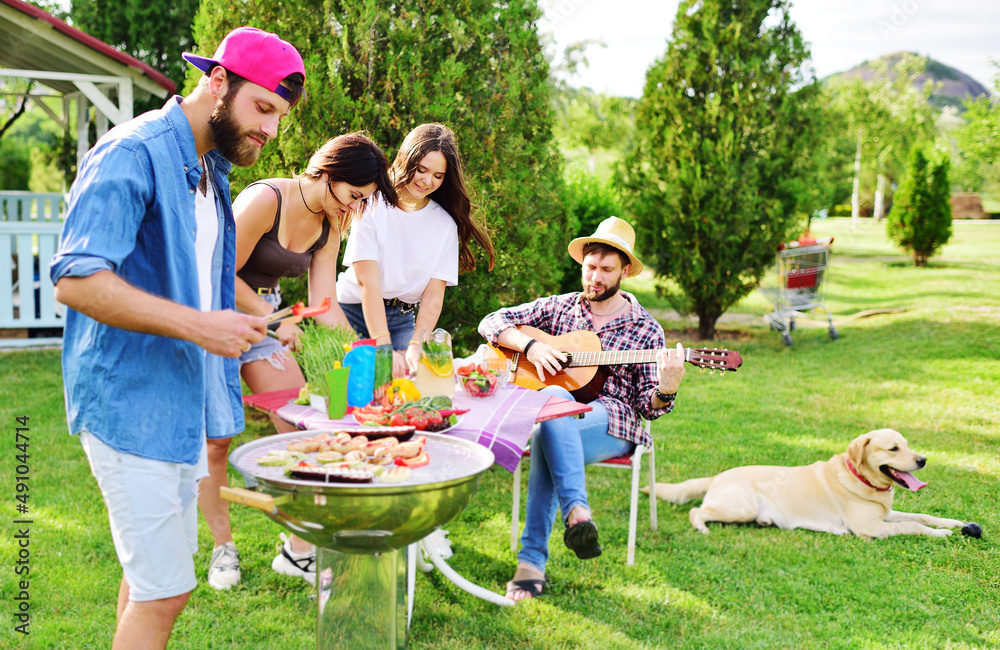 Φωτογραφία group of friends in the park at a picnic are barbecued, chatting, smiling and pl