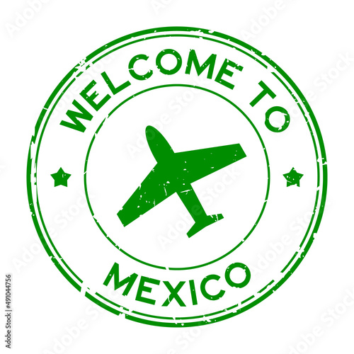Grunge green welcome to Mexico word with airplane icon round rubber seal stamp on white background