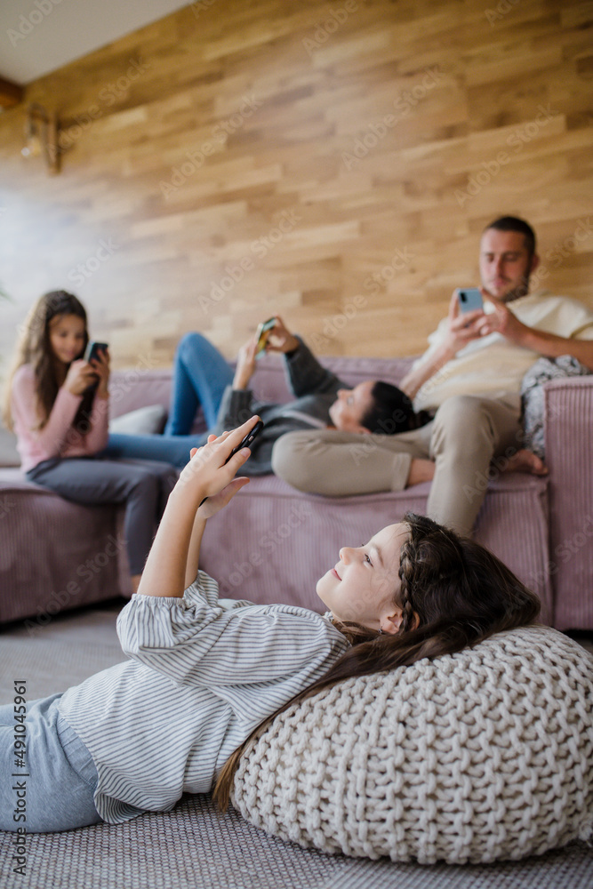 Family with two little daughters, everyone is using mobile phone in the living room. Family with two little daughters, everyone is using mobile phone in the living room.
