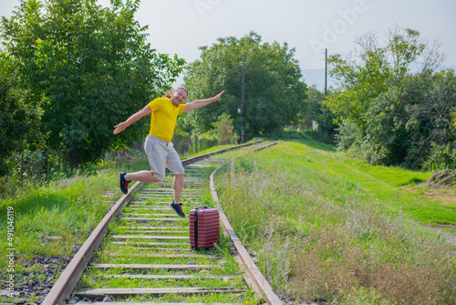 Fototapeta Naklejka Na Ścianę i Meble -  happy newcomer with a suitcase jumping on the railroad