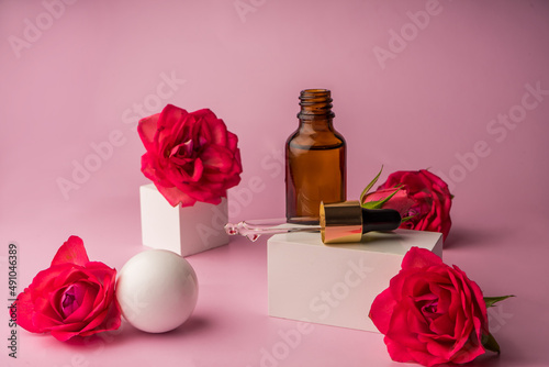 Glass bottle for drops and liquid and oils. Advertising of a cosmetology product. Roses. Pink water. OilFor Face and Body  photo