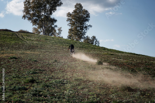 Hombre pilotando una moto de motocrós por el campo sin ningún tipo de protección dejando un rastro de polvo y tierra a su paso.