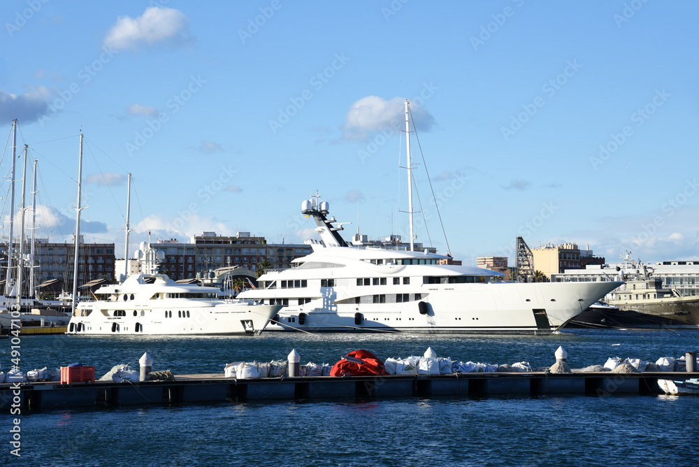 Yachts and motor boats in La Marina de Valencia, Spain. Luxury yacht and fishing motorboat in yacht club at Mediterranean Sea. Skiff and Sailboat in port. Yachting and sailing sport. Quai at ​Dock.