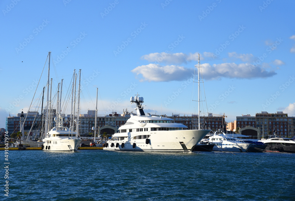 Yachts and motor boats in La Marina de Valencia, Spain. Luxury yacht and fishing motorboat in yacht club at Mediterranean Sea. Skiff and Sailboat in port. Yachting and sailing sport. Quai at ​Dock.