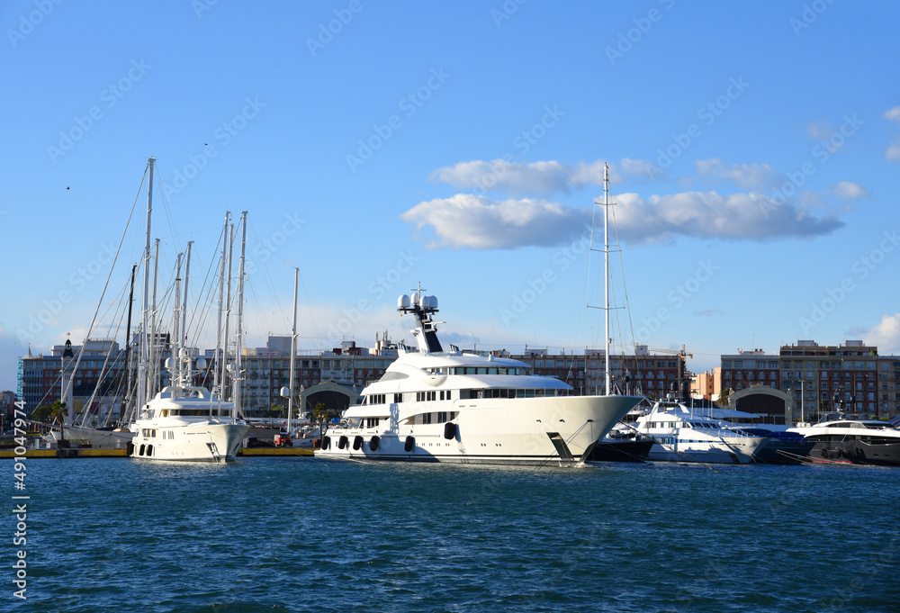 Yachts and motor boats in La Marina de Valencia, Spain. Luxury yacht and fishing motorboat in yacht club at Mediterranean Sea. Skiff and Sailboat in port. Yachting and sailing sport. Quai at Dock. Yachts and motor boats in La Marina de Valencia, Spain. Luxury yacht and fishing motorboat in yacht club at Mediterranean Sea. Skiff and Sailboat in port. Yachting and sailing sport. Quai at Dock.