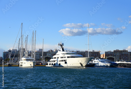 Yachts and motor boats in La Marina de Valencia, Spain. Luxury yacht and fishing motorboat in yacht club at Mediterranean Sea. Skiff and Sailboat in port. Yachting and sailing sport. Quai at ​Dock. © MaxSafaniuk