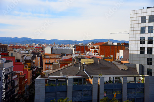 Colorful roofs of residential buildings in Barcelona. Colored building facade, windows and balconies with terraces. Panorama of city on the background of mountains with old facades of houses. © MaxSafaniuk
