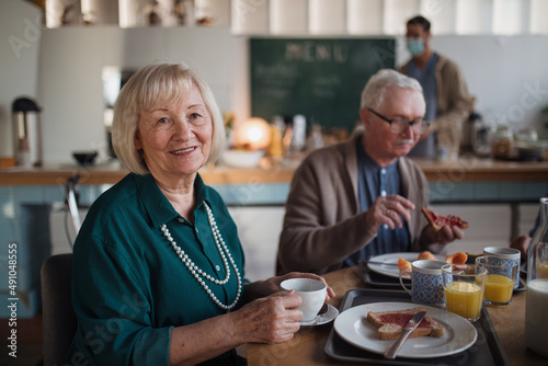 Smiling elderly woman and man enjoying breakfast in nursing home care center. © Halfpoint