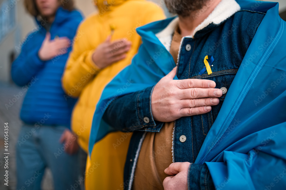Cropped shot of protestors with Ukrainian blue and yellow ribbons and flags protesting against war in Ukraine in street Cropped shot of protestors with Ukrainian blue and yellow ribbons and flags protesting against war in Ukraine in street