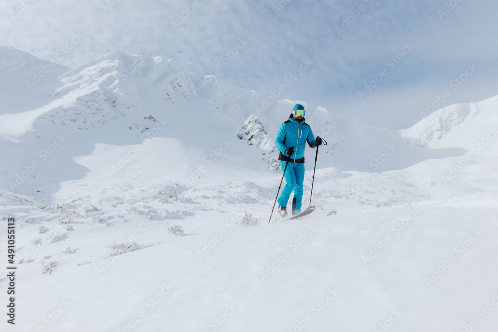 Male backcountry skier hiking to the summit of a snowy peak in the Low Tatras in Slovakia.
