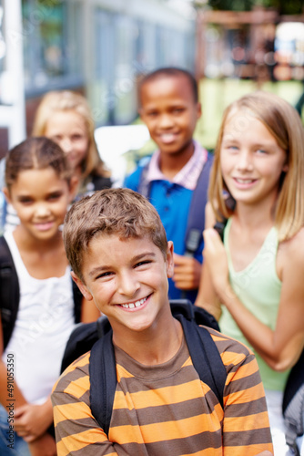 Full of confidence with a great group of friends. Happy young schoolboy with his friends standing behind him - copyspace.