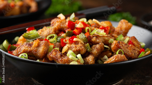 Stir fry salt and pepper pork loin with herbs in black bowl. Asian food