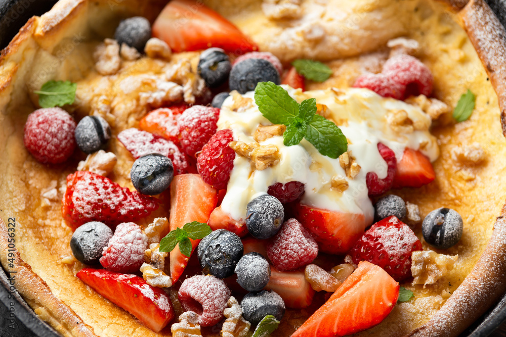 Dutch baby pancake with berries and icing sugar in a iron cast pan. Morning breakfast Dutch baby pancake with berries and icing sugar in a iron cast pan. Morning breakfast