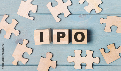 Blank puzzles and wooden cubes with the text IPO Initial Public Offering lie on a blue background