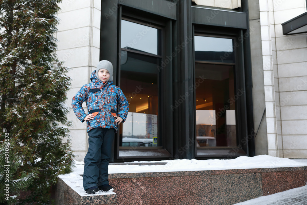 Child on curb of building in winter