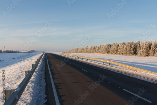 Wintercountry road. Winter landscape. A long straight road. Winter road through snowy fields. Winter