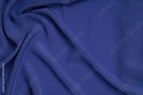 Abstract blue background. Navy blue silk satin texture background. Beautiful soft wavy folds on shiny fabric.