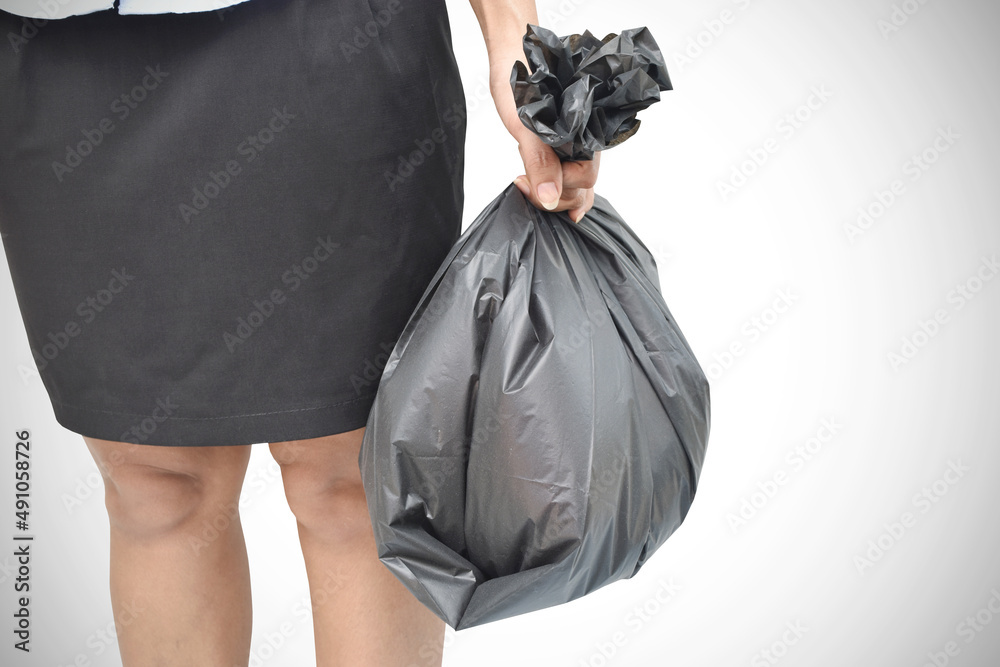 Hand holding a black garbage bag on white background. Hand holding a black garbage bag on white background.