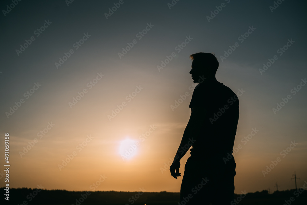 Silhouette of a man standing on a meadow at sunset