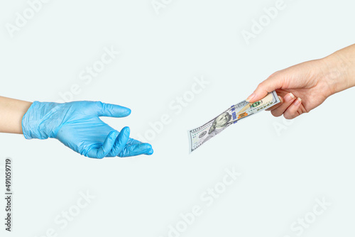 Closeup hand giving money another hand in blue medical glove on white background.