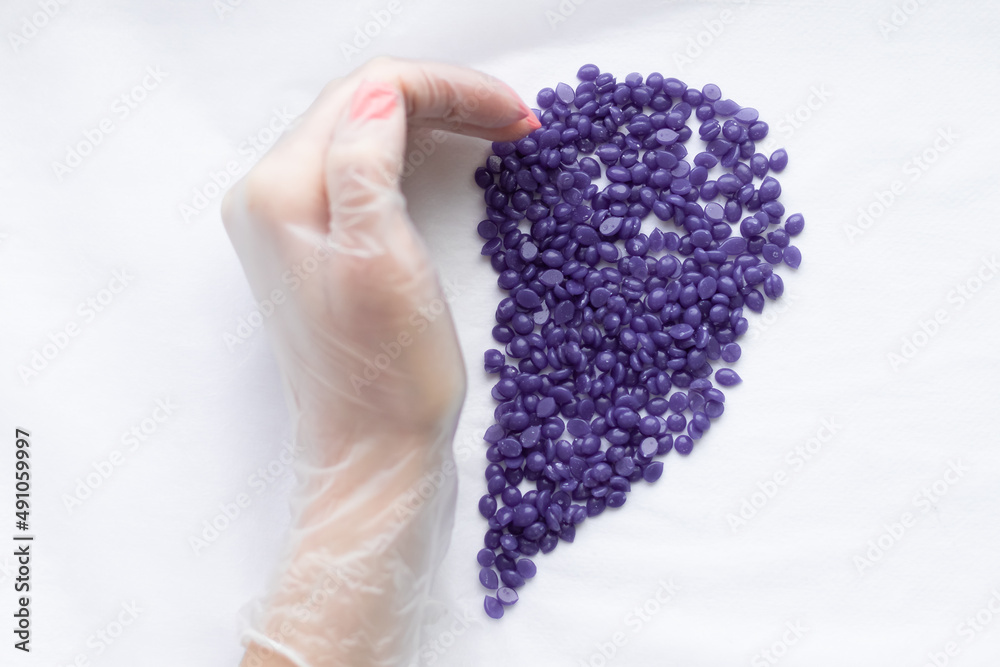 a gloved hand and depilation wax in the form of a heart. The concept of sugaring a gloved hand and depilation wax in the form of a heart. The concept of sugaring