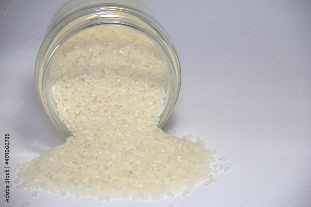 White rice poured from a transparent jar. White rice poured from a transparent jar.