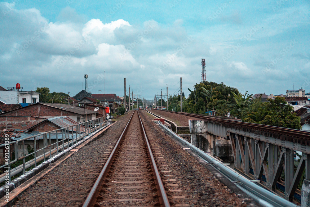 Railroad made of iron, wood and gravel in the middle of suburban settlements and over rivers in Indonesia