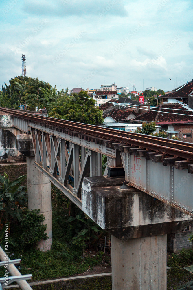  Railroad made of iron, wood and gravel in the middle of suburban settlements and over rivers in Indonesia