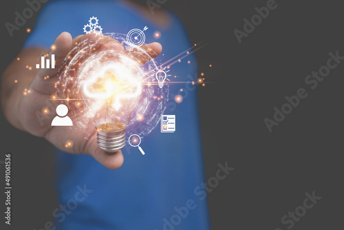 Technology business transformation concept. Innovation to the future. A man holding a light bulb with business icons, and virtual cloud computing to transfer database information upload, download.