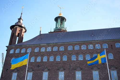 Ukraine and Sweden flag on pole waving in wind. Swedish and ukrainian symbol in front of Stockholm City hall world peace stadshuset photo