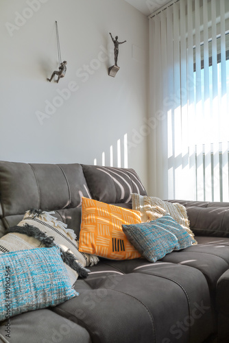 Sofa with colorful cushions and sunlight coming through the window and curtain.