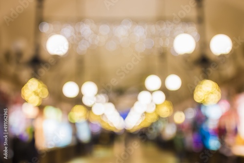 Background. In bokeh, evening city, Christmas trees, lamps, lights and ornaments. Tree alley in background. Christmas atmosphere for markets, city centers. People.