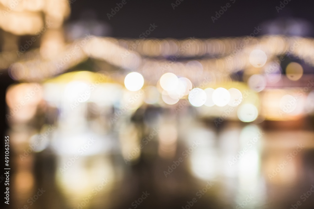 Background. In bokeh, evening city, Christmas trees, lamps, lights and ornaments. Tree alley in background. Christmas atmosphere for markets, city centers. People.