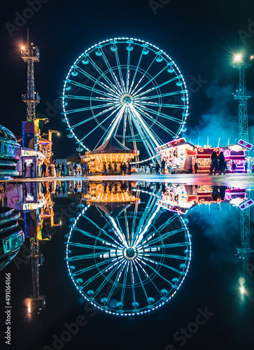 Drone view of colorful ferris wheel on during night time with reflection.