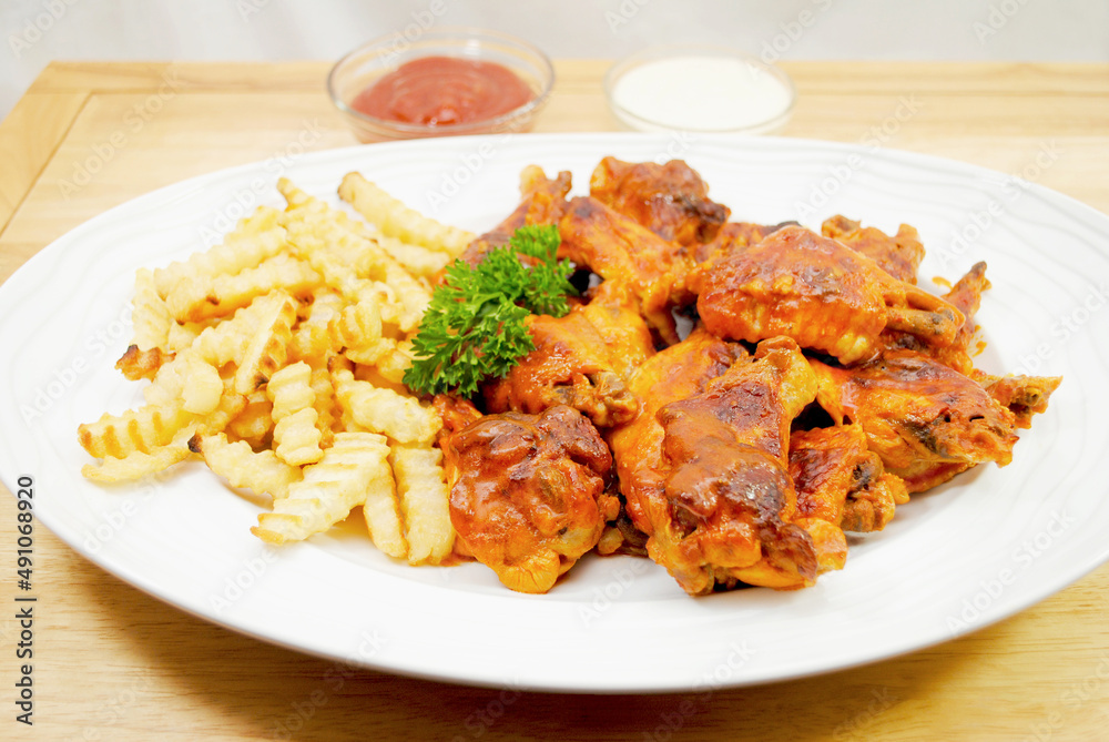 A Platter of French Fries Served and Spicy baked Buffalo Wings A Platter of French Fries Served and Spicy baked Buffalo Wings
