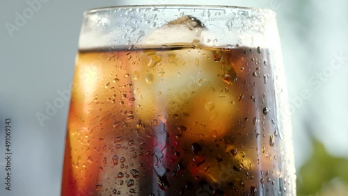 Ice cubes rolling on a glass with tasty refresing cola soda drink photo