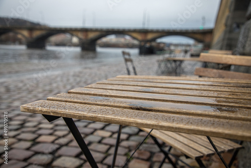 waterfront and abandoned tables in front of a cafe under the autumn rain