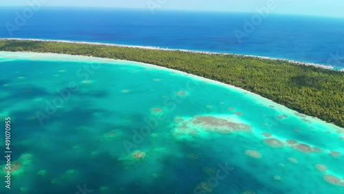 Flying high over a turquoise lagoon towards a tropical atoll in the Pacific Ocean photo