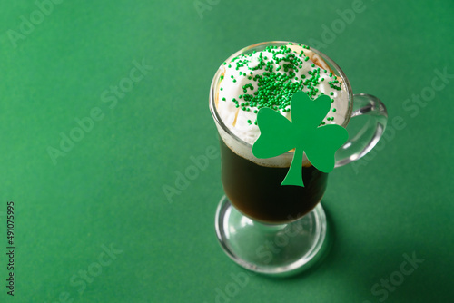 Patrick's Day celebration with Irish coffee in glass cup with sprinkles on green background. Copy space. Close up. photo