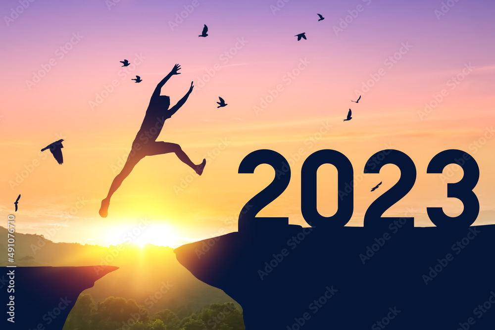 Silhouette man jumping between cliff to 2022 and birds flying at top of mountain. Freedom challenge and travel adventure holiday concept. Silhouette man jumping between cliff to 2022 and birds flying at top of mountain. Freedom challenge and travel adventure holiday concept.