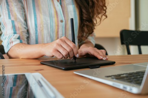 Close Up Photo of Woman Hands Drawing Something on a Graphic Tablet and Laptop Computer while Sitting at Home Office Desk