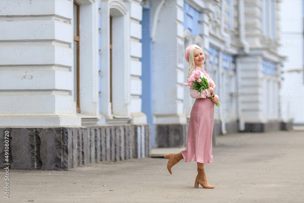 Girl holds bouquet of flowers and inhales their fragrance. Pretty girl takes lovely tulips with joy and smile. Portrait of surprised woman smelling flowers on the street.Girl holds bouquet of flowers