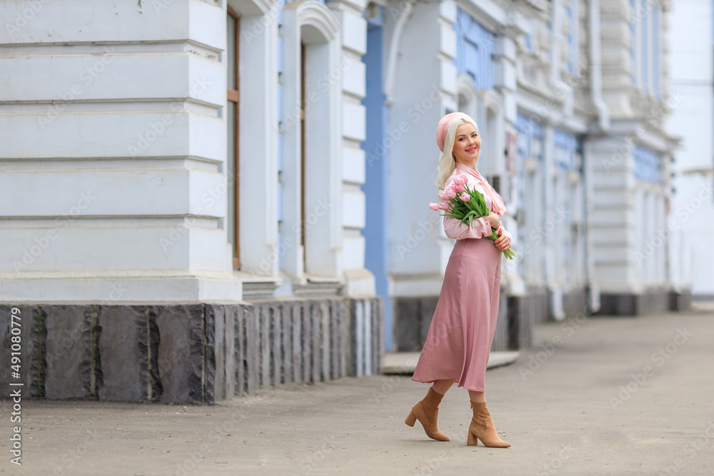 Girl holds bouquet of flowers and inhales their fragrance. Pretty girl takes lovely tulips with joy and smile. Portrait of surprised woman smelling flowers on the street.Girl holds bouquet of flowers Girl holds bouquet of flowers and inhales their fragrance. Pretty girl takes lovely tulips with joy and smile. Portrait of surprised woman smelling flowers on the street.Girl holds bouquet of flowers