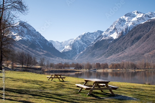 Canvas Print Beautiful view of a picnic area on the shores of Genos Loudenvielle lake, France, with snow-capped mountains in the background