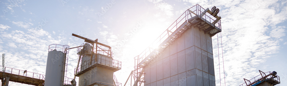 Manufacturing plant with industrial buildings, construction systems and ladders under cloudy sky Manufacturing plant with industrial buildings, construction systems and ladders under cloudy sky
