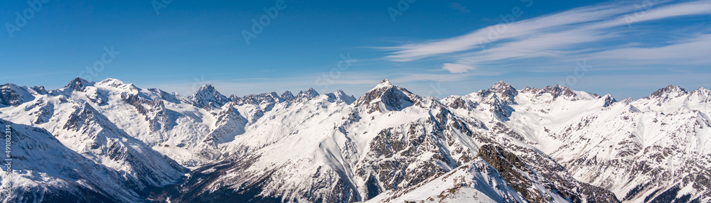 Panoramic view of winter snowy mountains in Caucasus region in Russia with blue sky Panoramic view of winter snowy mountains in Caucasus region in Russia with blue sky