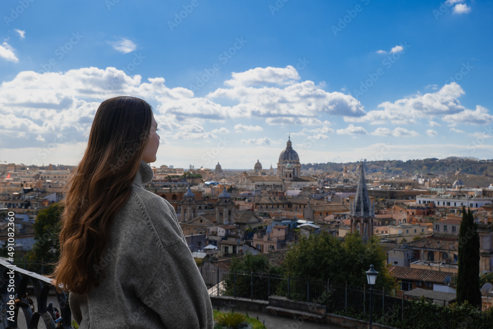 Naklejka premium Young tourist woman with long dark hair looks at the panorama view of Rome from above